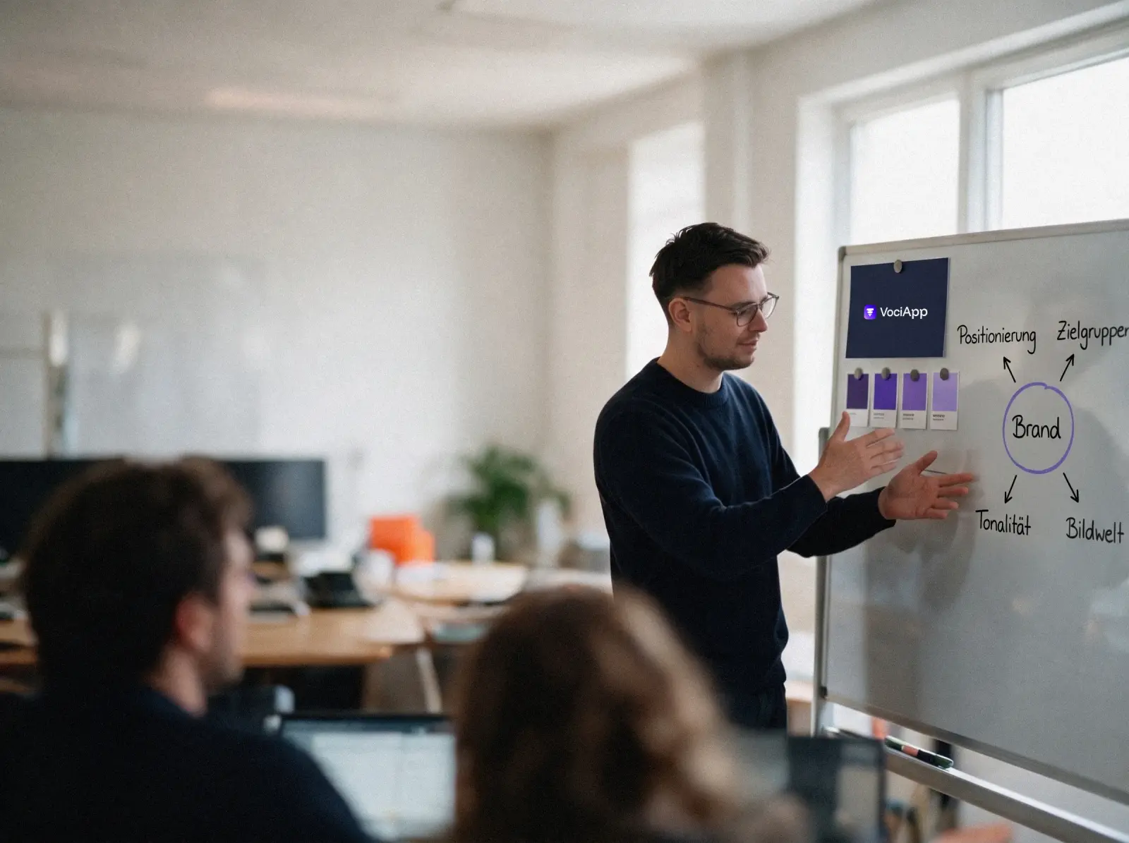 Alex Dreger erklärt am Whiteboard die Positionierung von VociApp: Logo, Farbmuster und eine Mindmap mit Positionierung, Zielgruppen, Tonalität und Bildwelt
