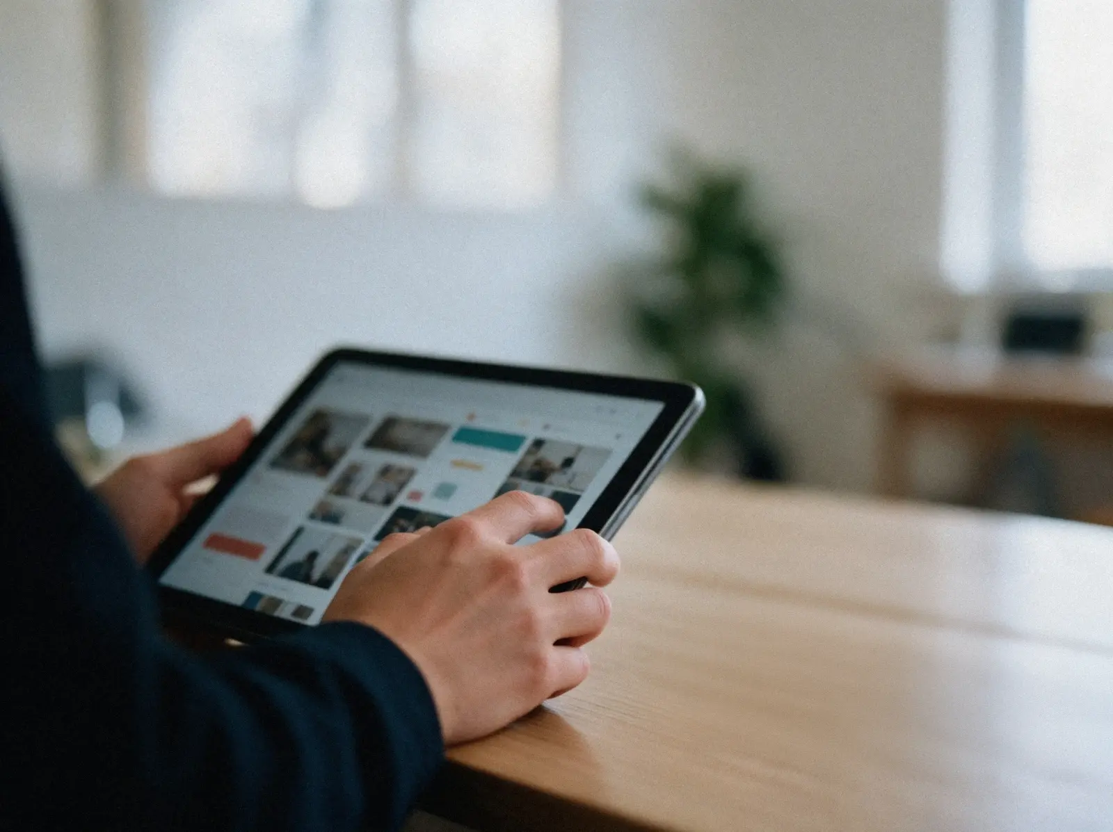 Eine Hand hält ein Tablet mit Entwürfen für Social-Media-Beiträge, daneben liegen Farbmuster